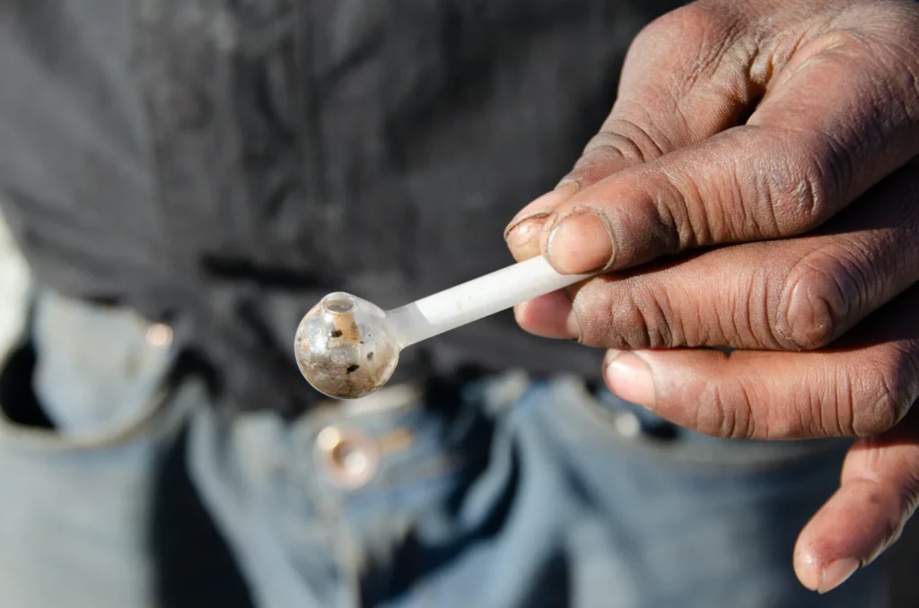 A man holding a meth pipe; is in need of treatment here at Asana Recovery.