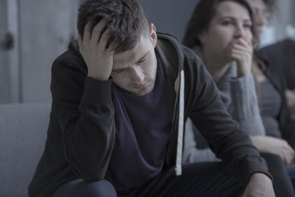 photo of depressed man with alcoholism problem sitting in dark rehab center