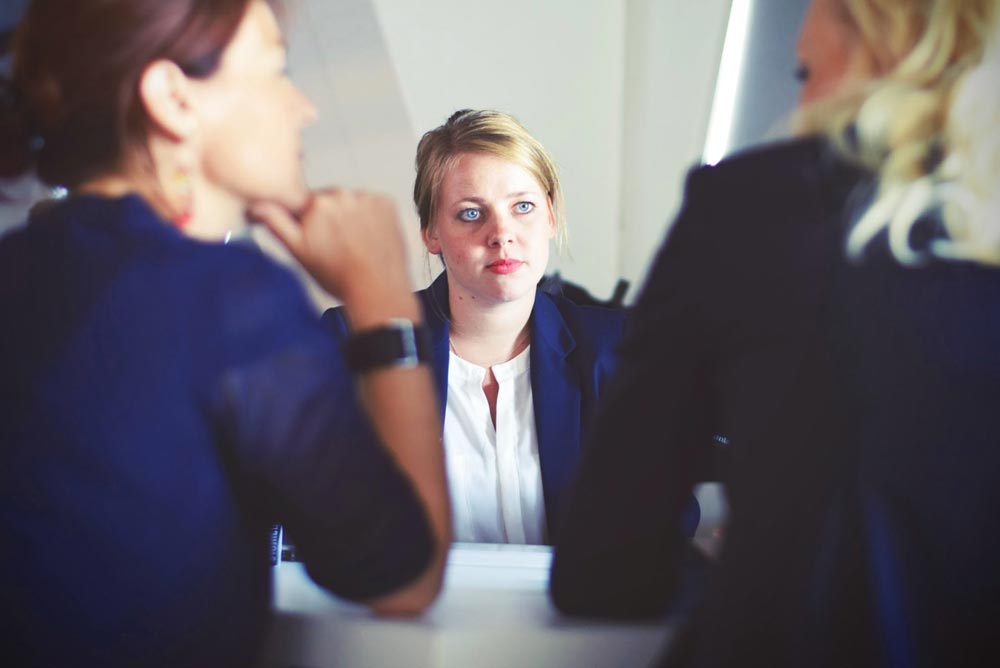 photo of a female employee being interview by her employer and an HR assistant