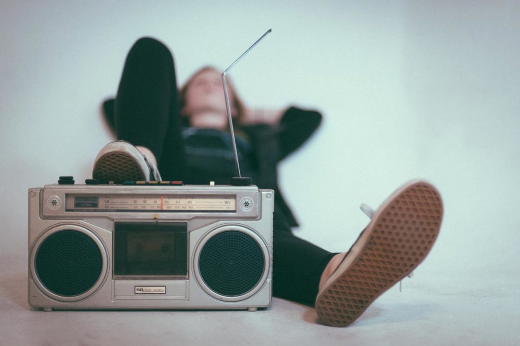 photo of a woman laying on bed near gray radio