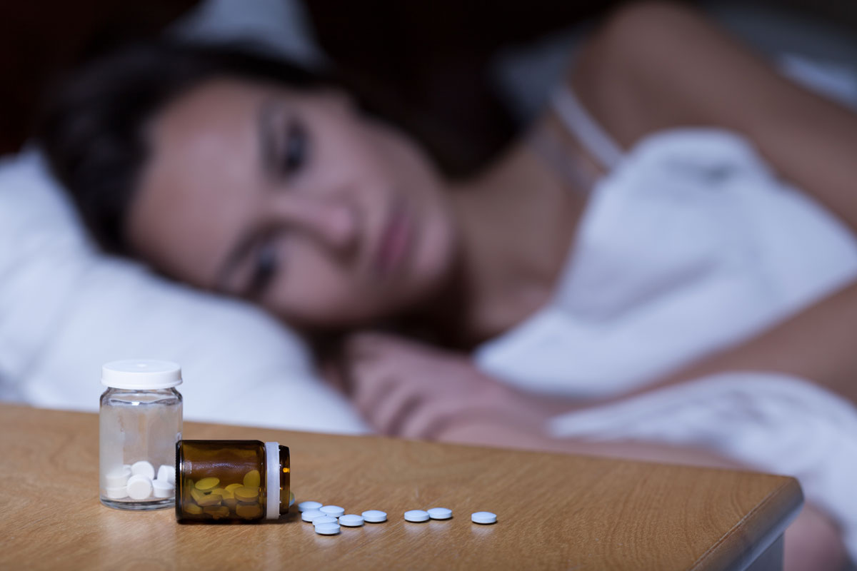 photo of a Woman lying in bed, taking sleeping pills