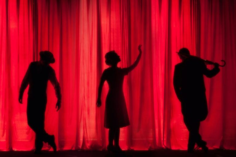 photo of silhouette of three people performing on stage