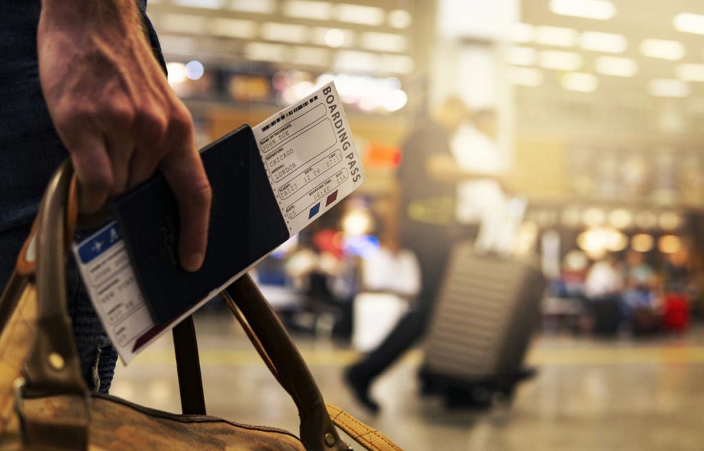 a man holding a travel boarding pass and a bag in the airport