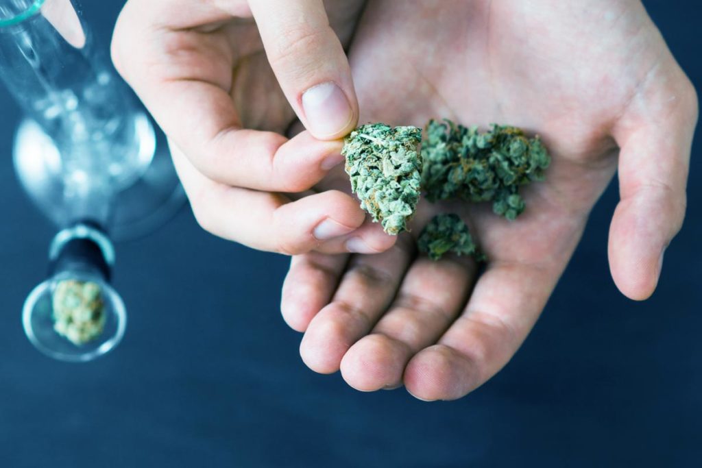 Hands of a man on Bong and medical marijuana, cannabis thc flower Sativa and Indica Close up on a black background