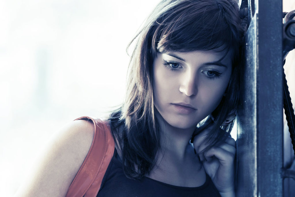 thoughtful young girl leaning against the wall