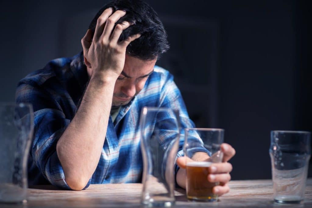 a man wearing checkered polo drinking alcohol