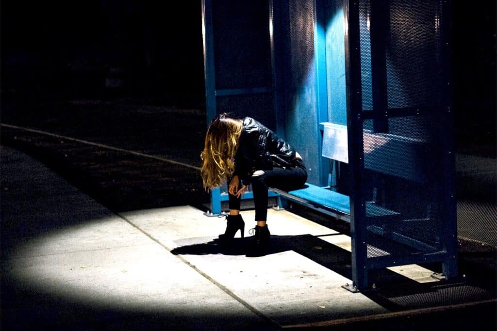 Celebrity Drug Deaths in 2022, a glamour woman sitting on a bench with spotlight on