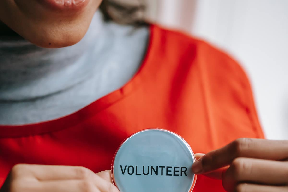 a young woman holding a circle pin for volunteers
