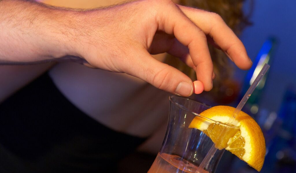 A man dropping drugs into his date's drink; if you suspect this happened to you, give us a call.