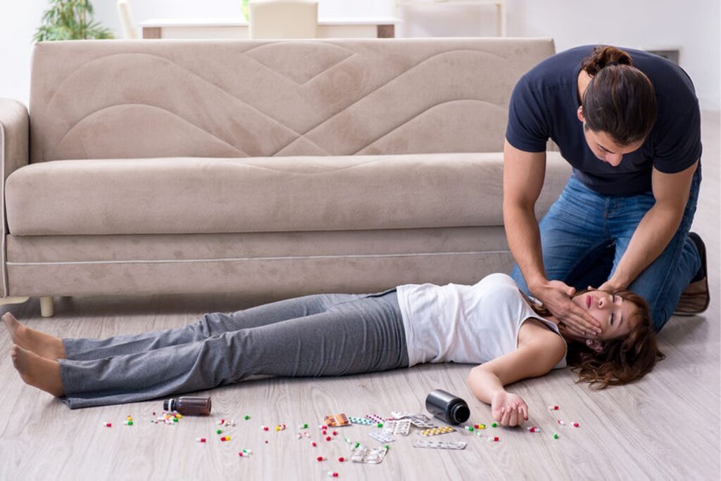 A young lady experiencing an overdose; while her friend attempts to help.